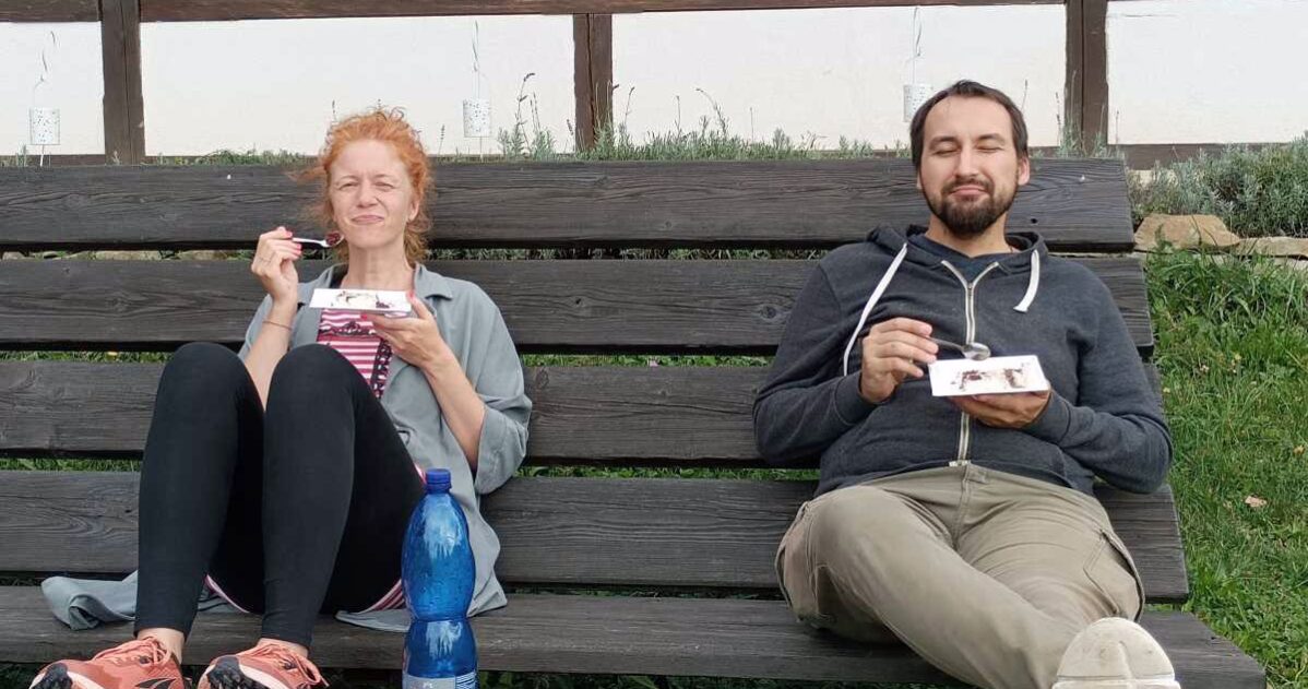 Muž a žena jí zákusky na lavičce venku MADIO