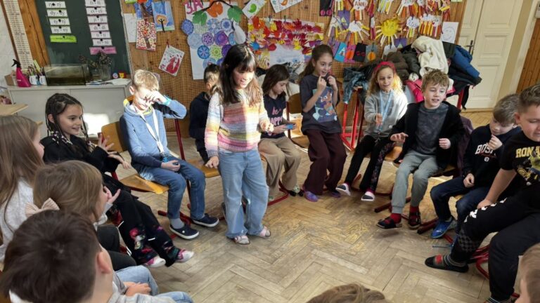 Žáci sedící v kruhu, jedna dívka stojí MADIO