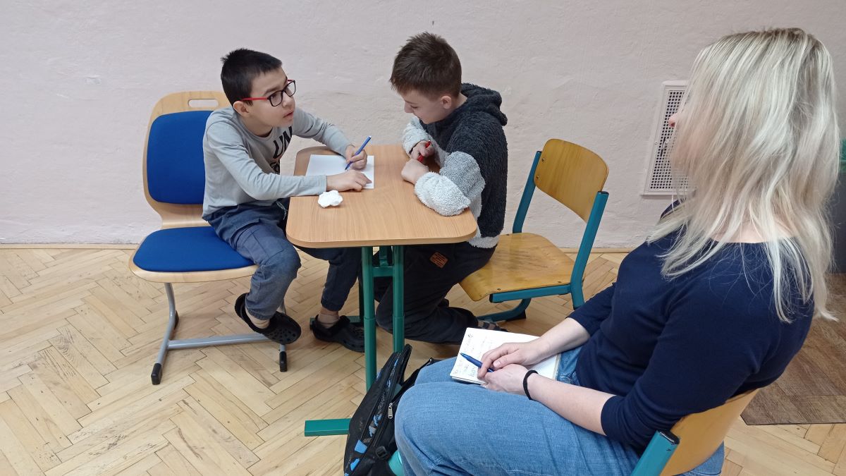 Učitelka sleduje dva žáky při rozhovoru MADIO